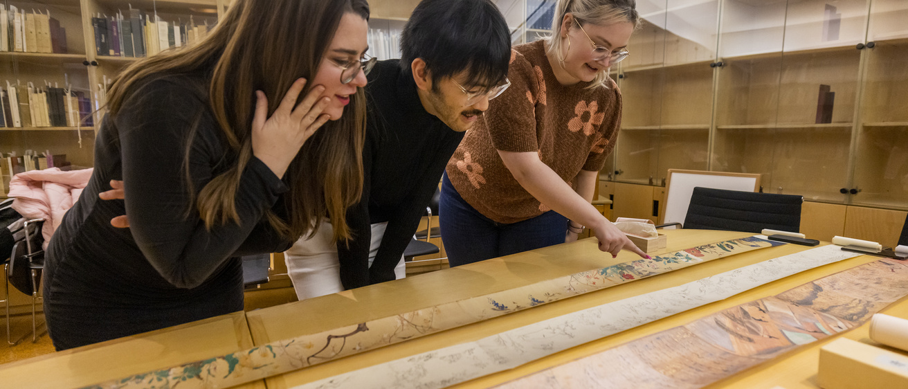art history students looking at scrolls