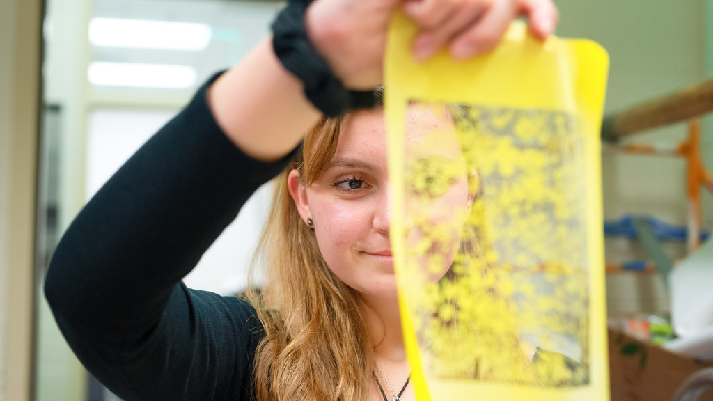 art student holding up beautiful yellow graphic image